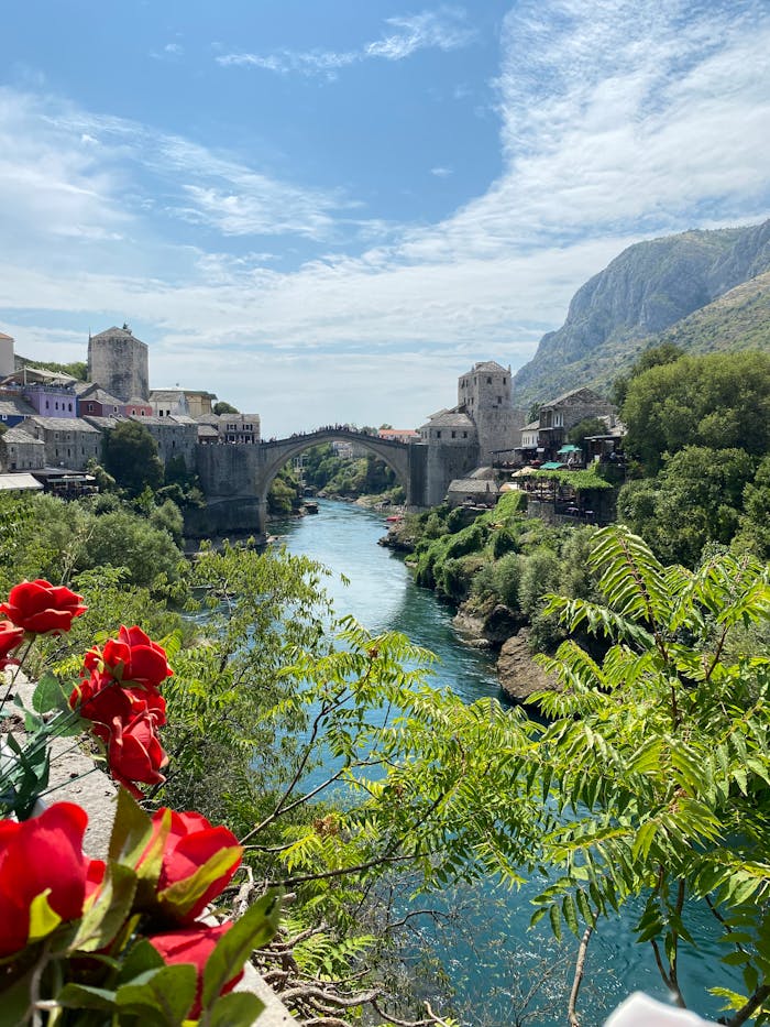 Captivating view of the Old Bridge and river in Mostar, Bosnia with vibrant flowers in the foreground.